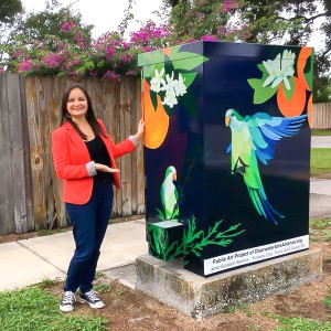 Elizabeth Barenis is shown standing next to the signal box which has her original image of parrots on it.