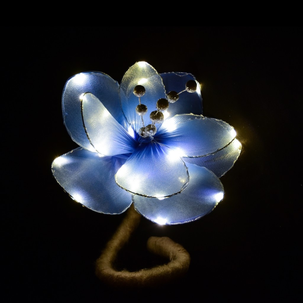 A blue, light-up flower sculpture is shown against a black background.